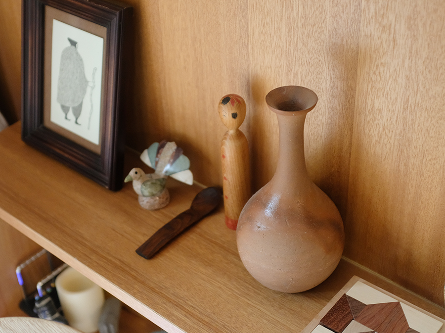 本棚の中に置かれた素焼きの花瓶や民芸品